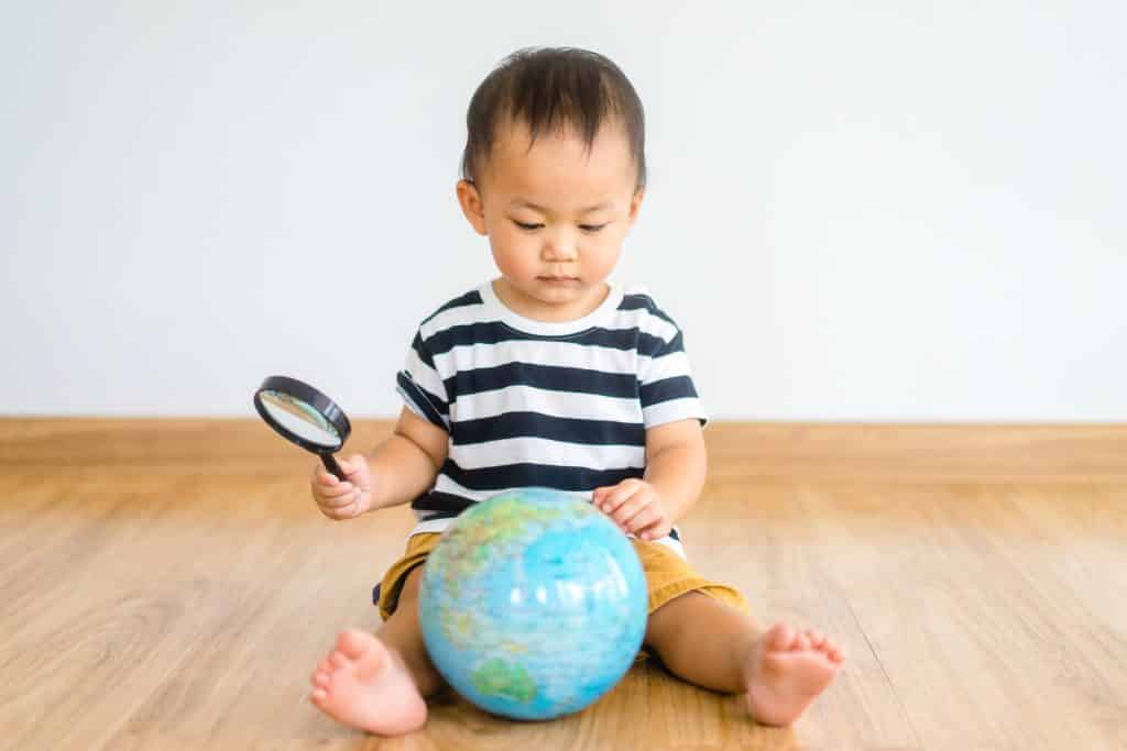 baby boy Looking At Globe Through Magnifying Glass