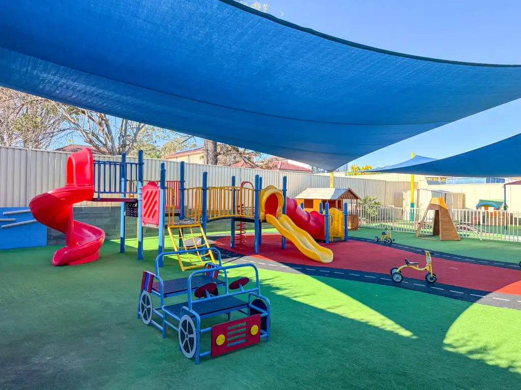Outdoor Montessori playground at Auburn Albert Road childcare with slides, climbing equipment and shaded play area