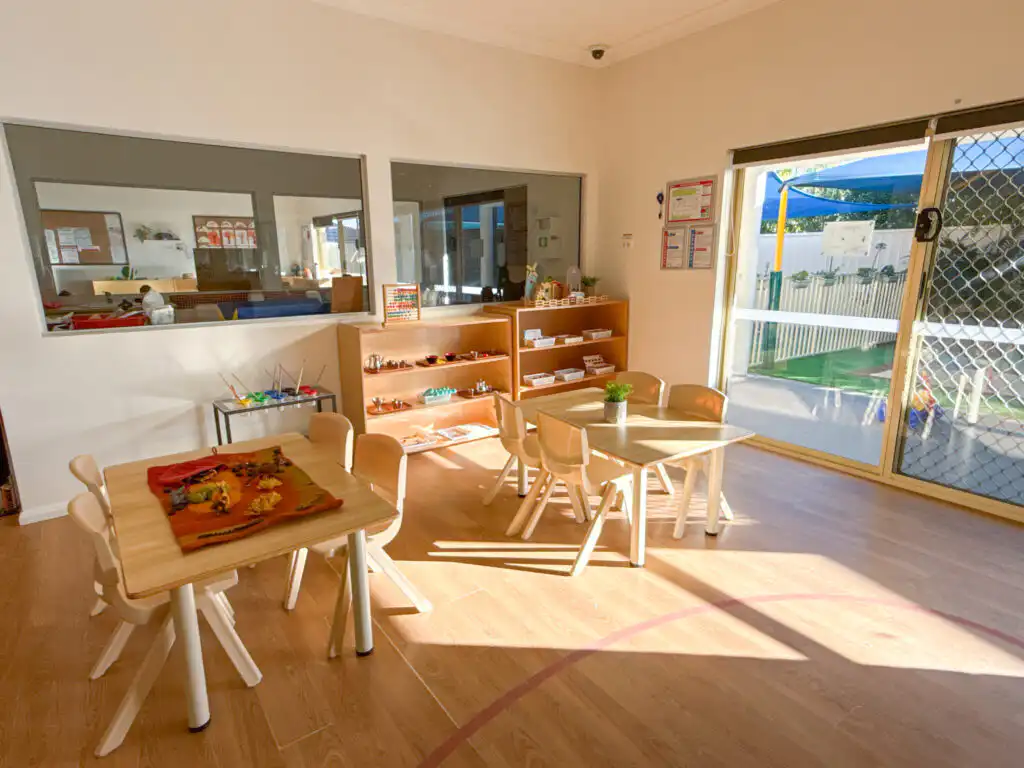 Montessori classroom at Auburn Albert Road childcare with wooden tables, learning shelves and natural light from outdoor access