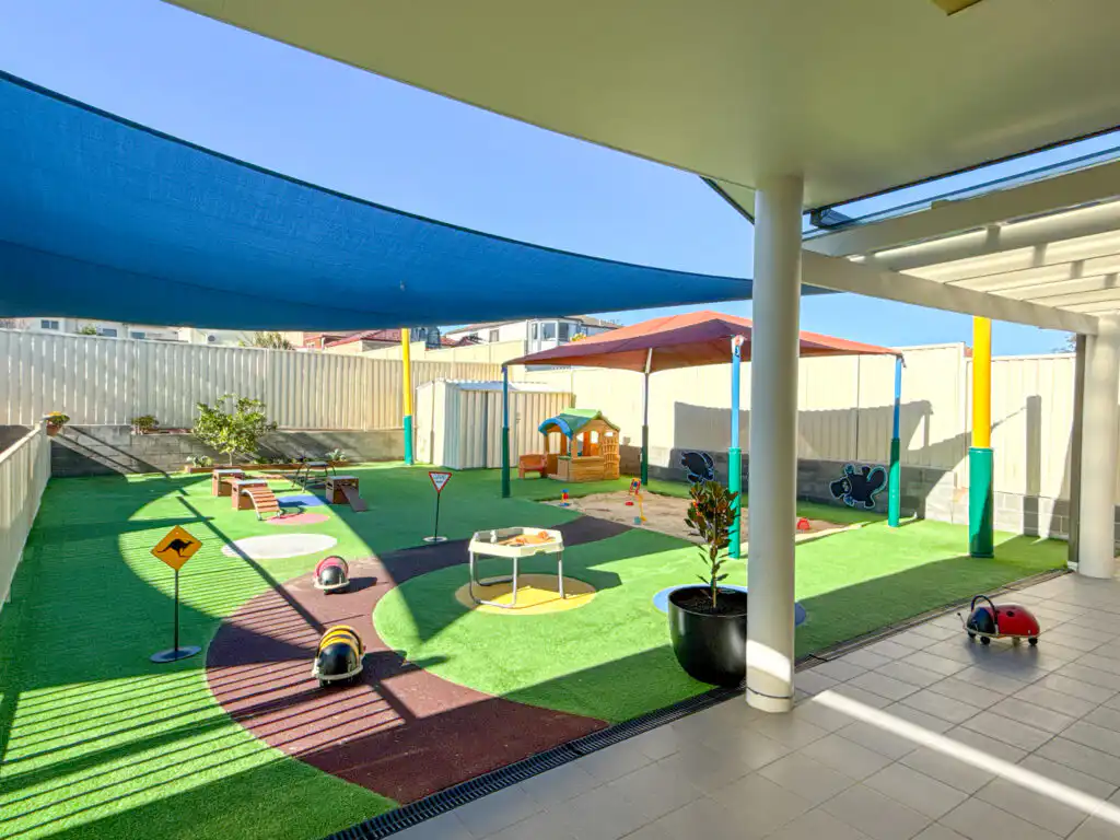 Outdoor Montessori play area at Auburn Albert Road childcare with tricycle track, shaded zones, playhouse and activity stations