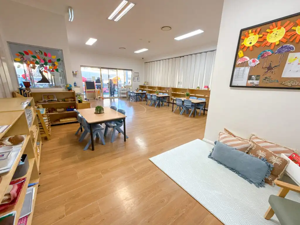 Montessori classroom at Auburn Albert Road childcare with learning shelves, group tables, quiet corner and outdoor access
