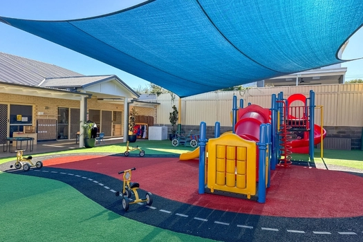 Shaded outdoor playground at Auburn Montessori Academy with slides, tricycle track and soft-fall play space