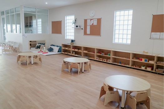 Spacious Montessori classroom at Auburn West Montessori Academy with round tables and learning shelves