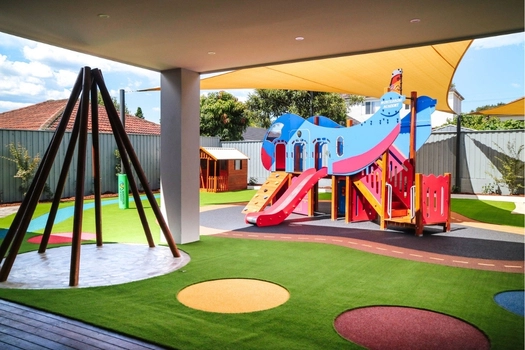 Outdoor playground at Auburn West Montessori Academy with slide, climbing equipment and shaded play space