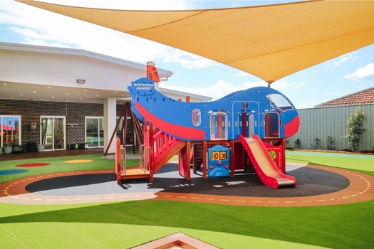 Shaded outdoor playground at Auburn West Montessori Academy with airplane play structure and slide