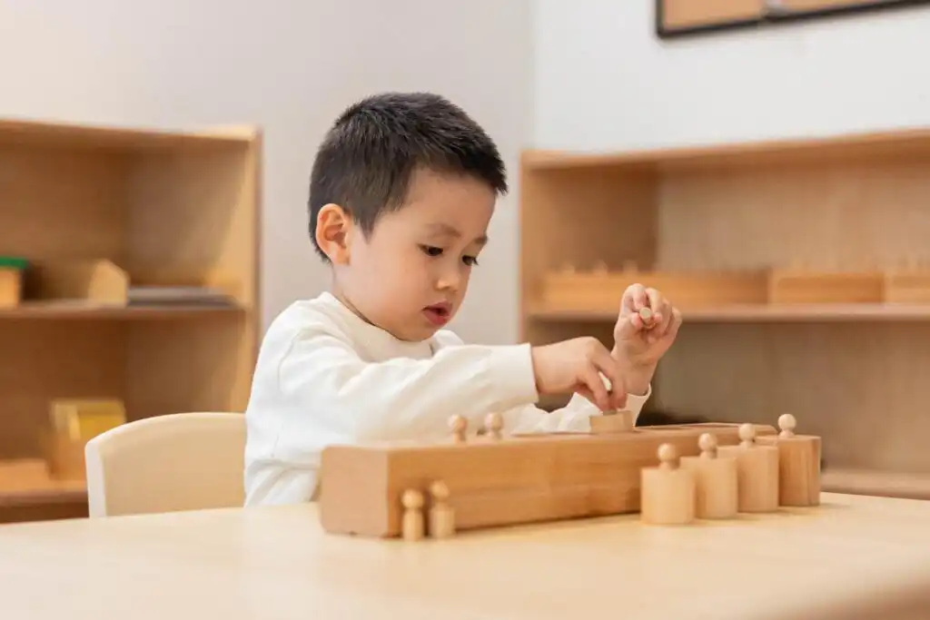 Child working with a Montessori cylinder activity
