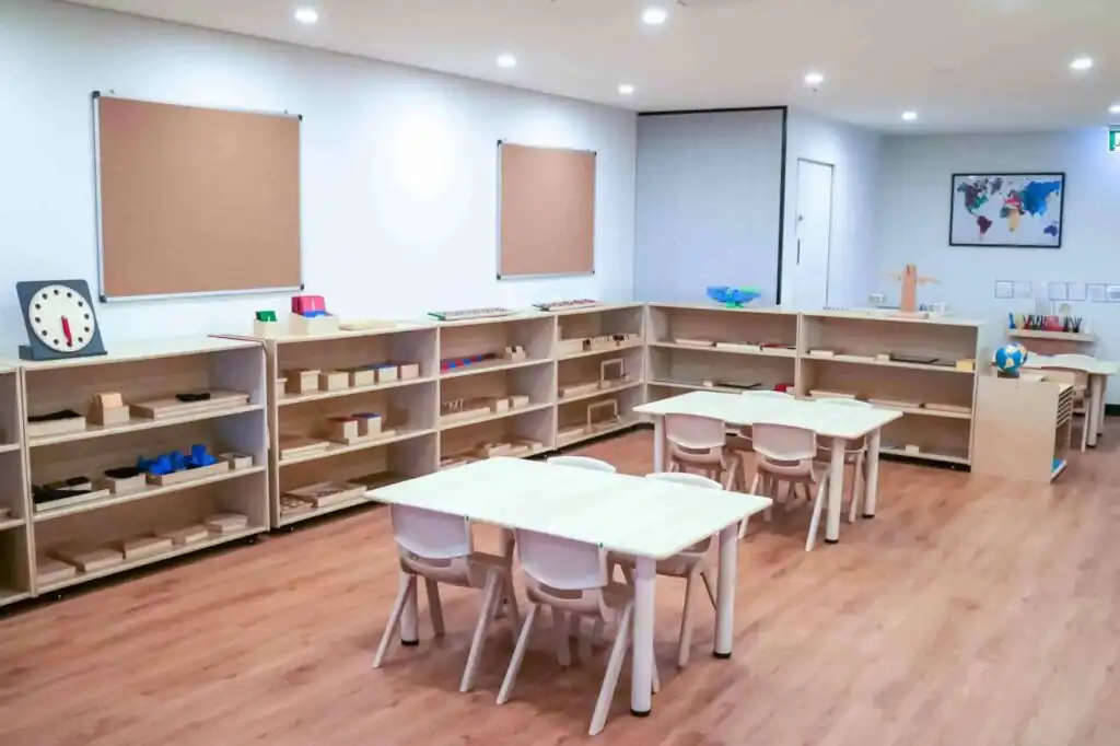 Montessori classroom at Crows Nest childcare with wooden tables, corner shelving and organised learning materials