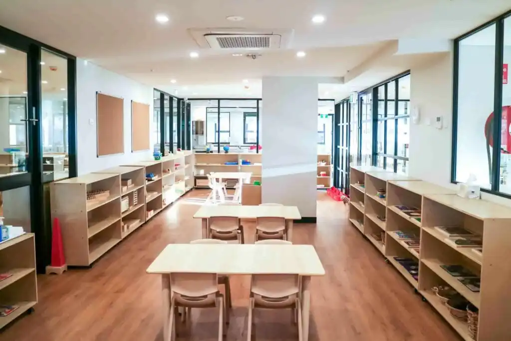 Montessori classroom at Crows Nest childcare with wooden tables, long learning shelves and glass partitioned learning spaces