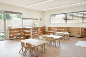 Childcare Montessori Preschool Classroom with open shelving, desks and chairs, and Montessori materials.
