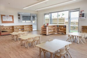 Childcare Montessori Preschool Classroom with open shelving, desks and chairs, and Montessori materials.