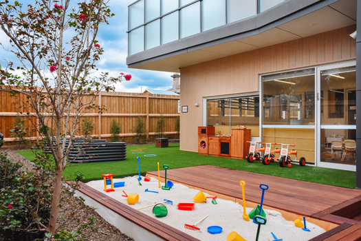 Outdoor sandpit and garden learning area at Elsternwick Montessori Academy childcare and kindergarten.