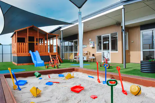 Sandpit and outdoor learning environment at Elsternwick Montessori Academy with cubby house and play equipment.