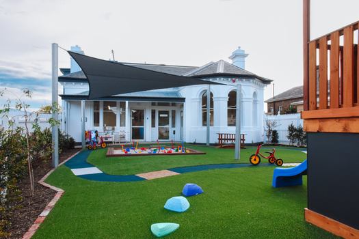 Elsternwick Montessori Academy outdoor playground with heritage building, shaded play areas, and open green spaces.