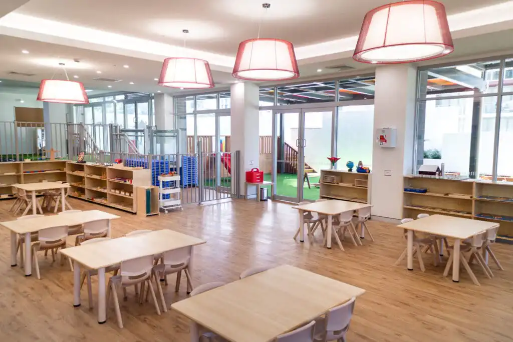 Preschool Classroom with Montessori Materials on shelves, with desks and chairs