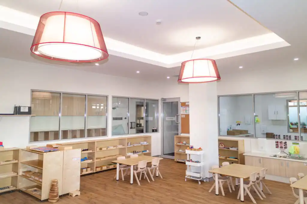Preschool Classroom with Montessori Materials on shelves, with desks and chairs