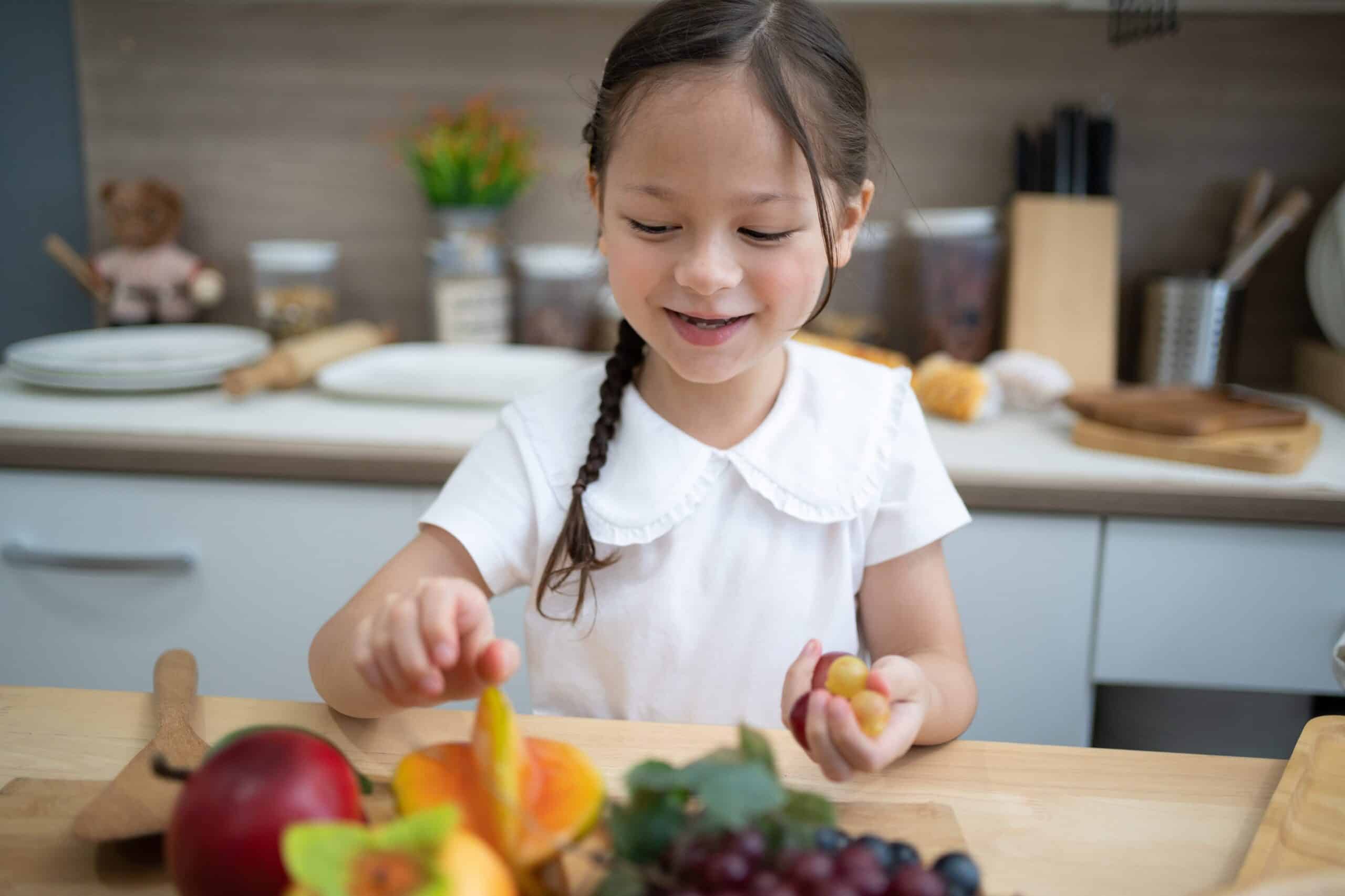 child playing with fruit in kitchen