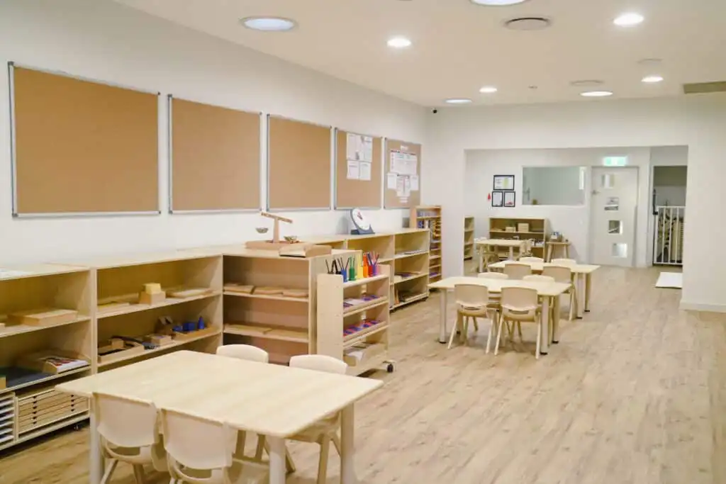 Classroom interior of Montessori Academy’s Guildford childcare, with small tables and shelves with educational materials.