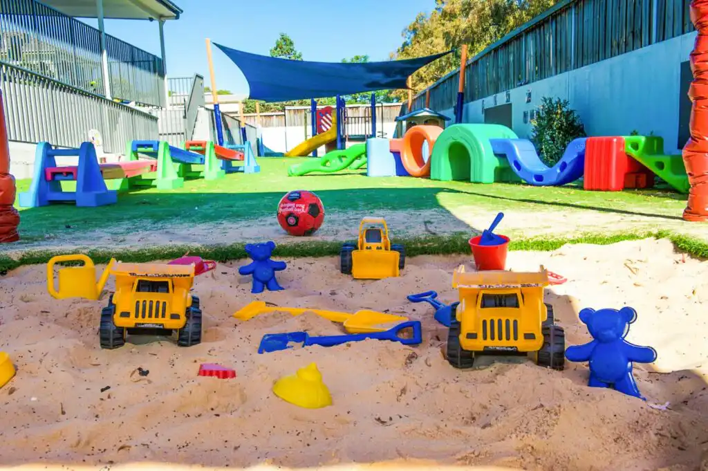 Sandpit at North Parramatta Montessori Academy with toy trucks and outdoor play equipment