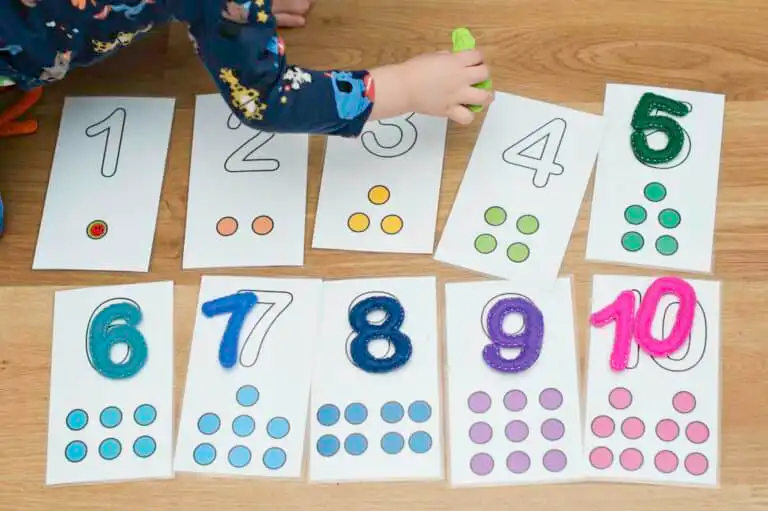 A child in pyjamas using Montessori number cards on a wooden floor.