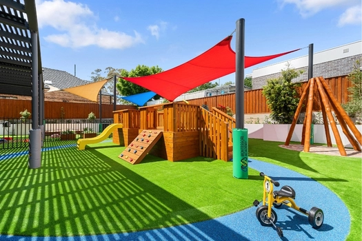Outdoor playground at Penrith Derby Street Montessori Academy with slide, climbing equipment and tricycle