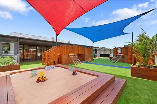 Shaded outdoor play area at Penrith Derby Street Montessori Academy with sandpit and climbing equipment