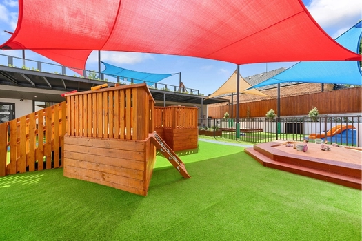 Shaded outdoor play area at Penrith Derby Street Montessori Academy with climbing equipment and sandpit