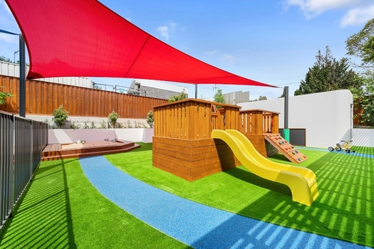 Shaded outdoor playground at Penrith Derby Street Montessori Academy with slide and climbing equipment