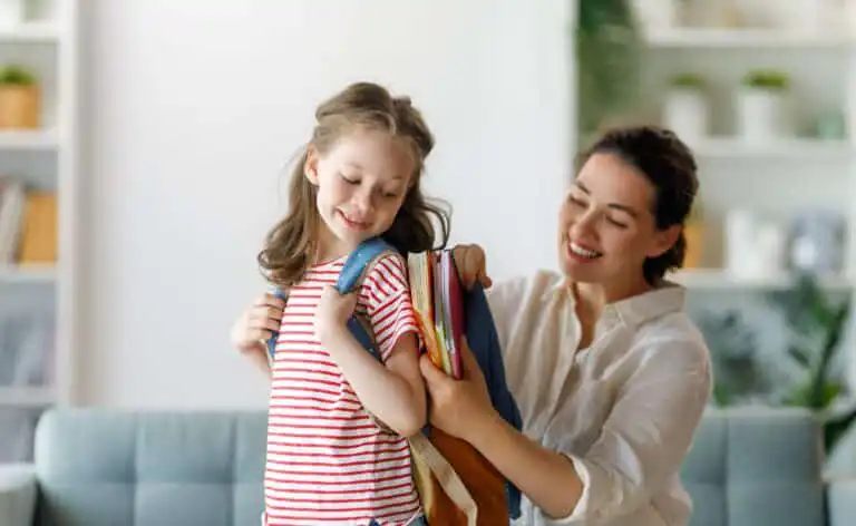 Woman help pack a child's backpack, ready for school