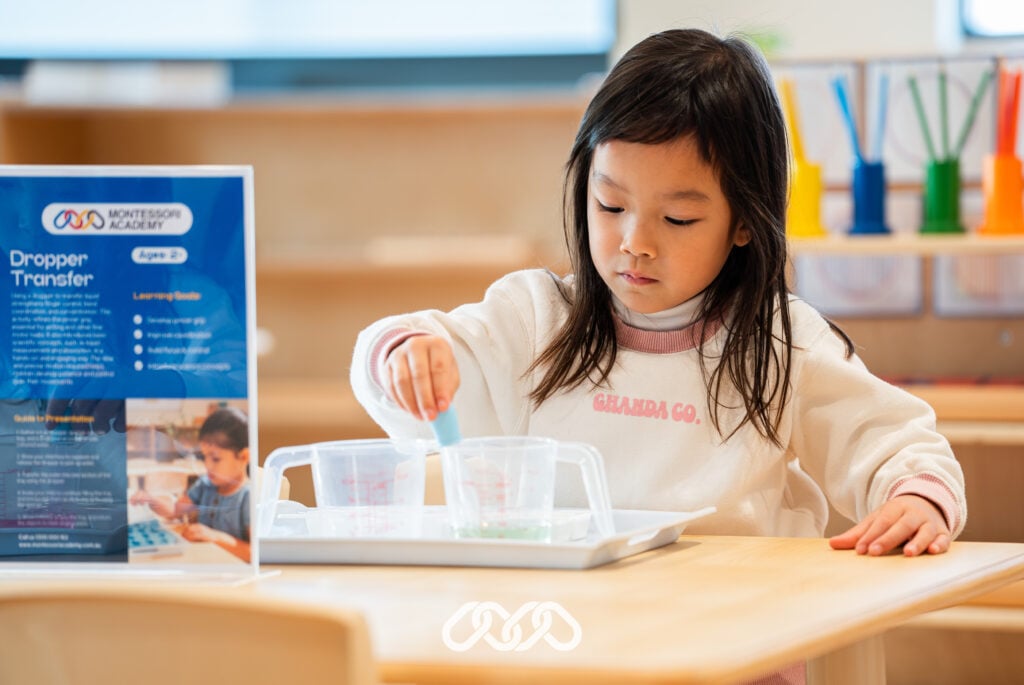 Child enjoys Montessori Dropper Transfer activity at Condell Park North grand opening event in preschool room.
