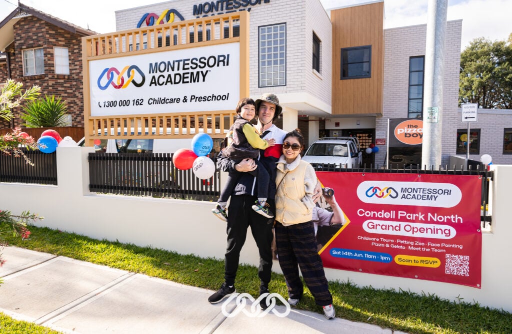 A young family gathers at the main entry of Condell Park North Montessori Academy, eagerly awaiting the start of the grand opening event.