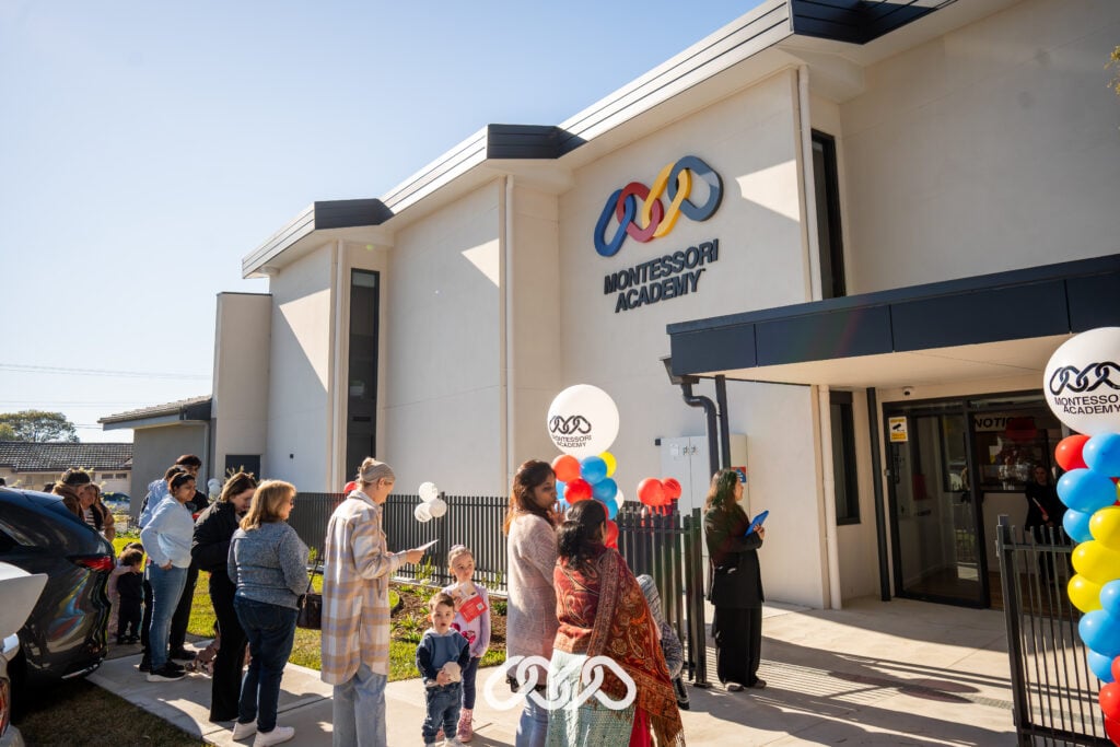 A line of family gathers at the main entry of St Marys Montessori Academy, eagerly awaiting the start of the grand opening event.