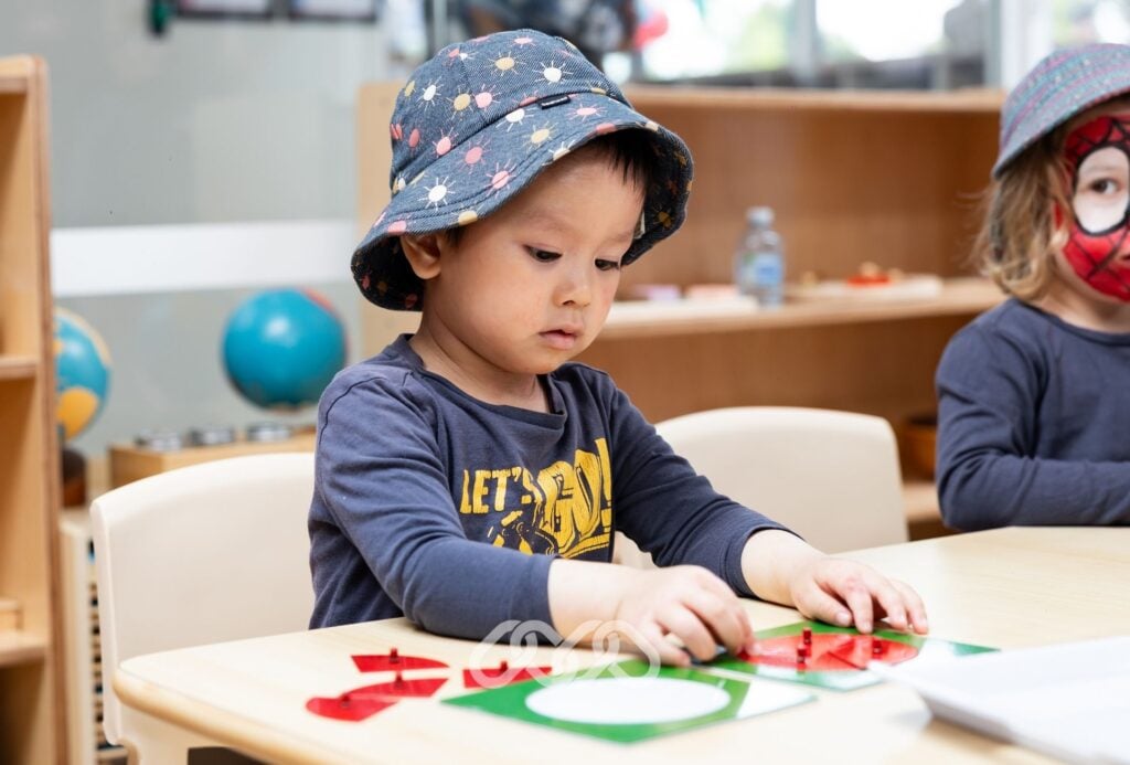 Child enjoys Montessori transfer activity at Winston Hills grand opening event in preschool classroom.