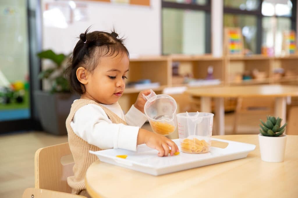 Montessori Infant engaged in practical life activity in nursery classroom for ages 0-2