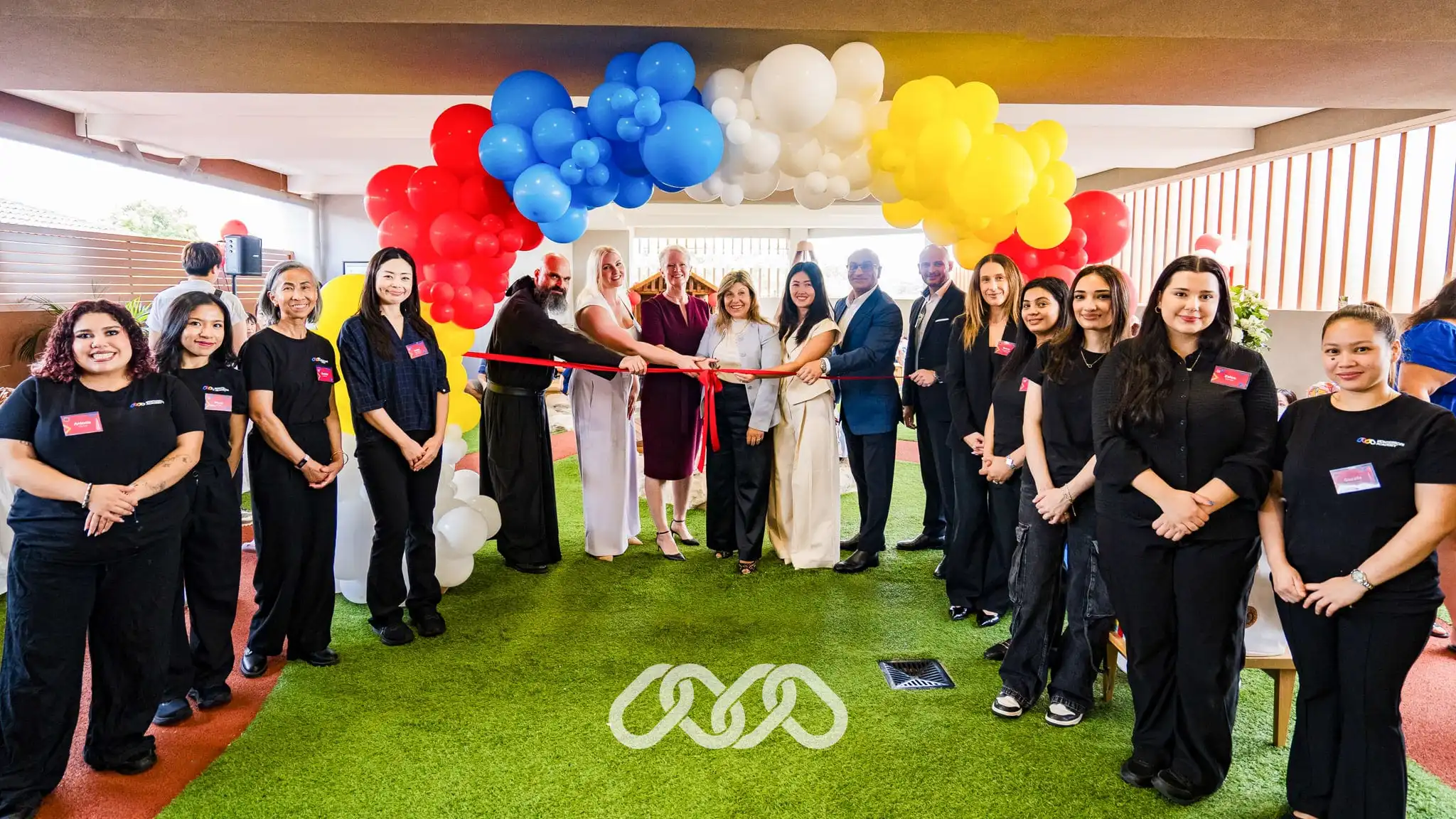Montessori Academy Leadership and Centre team gather under colourful balloon arch with local community leaders