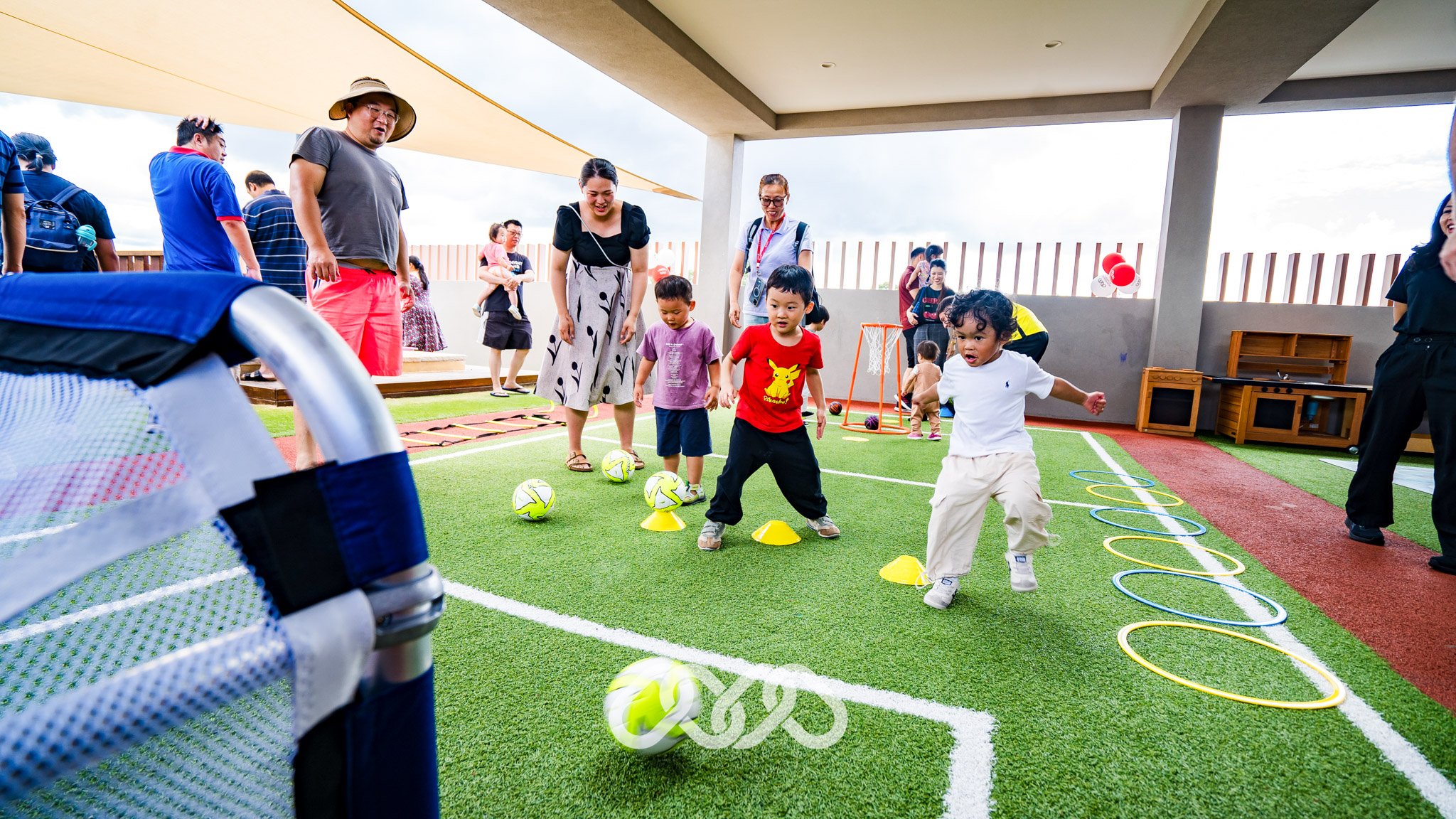 Children play with child sized soccer equipment on outdoor soccer pitch at Campsie montessori academy