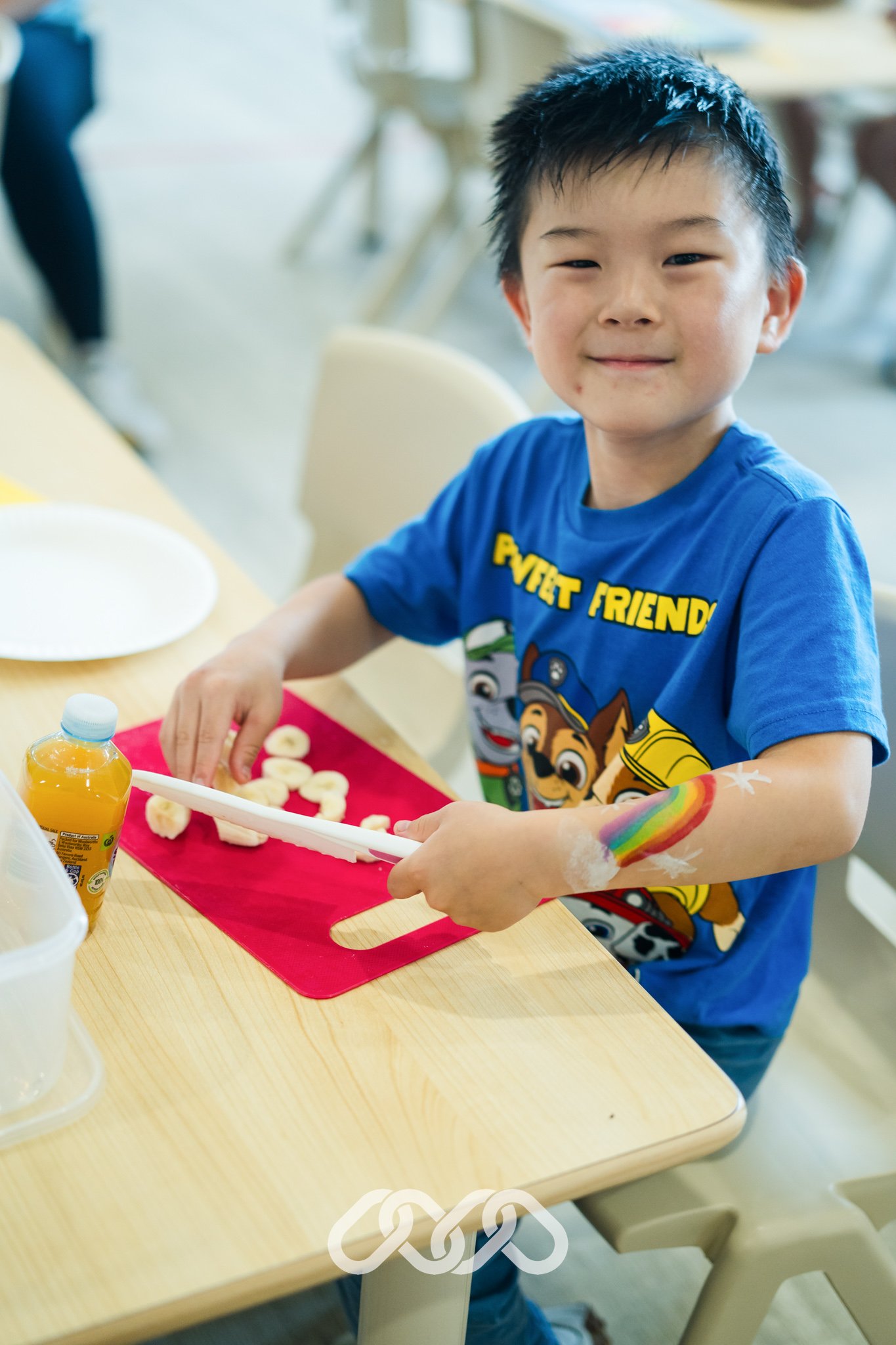 Child practises banana cutting through a practical life Montessori activity using a child safe knife