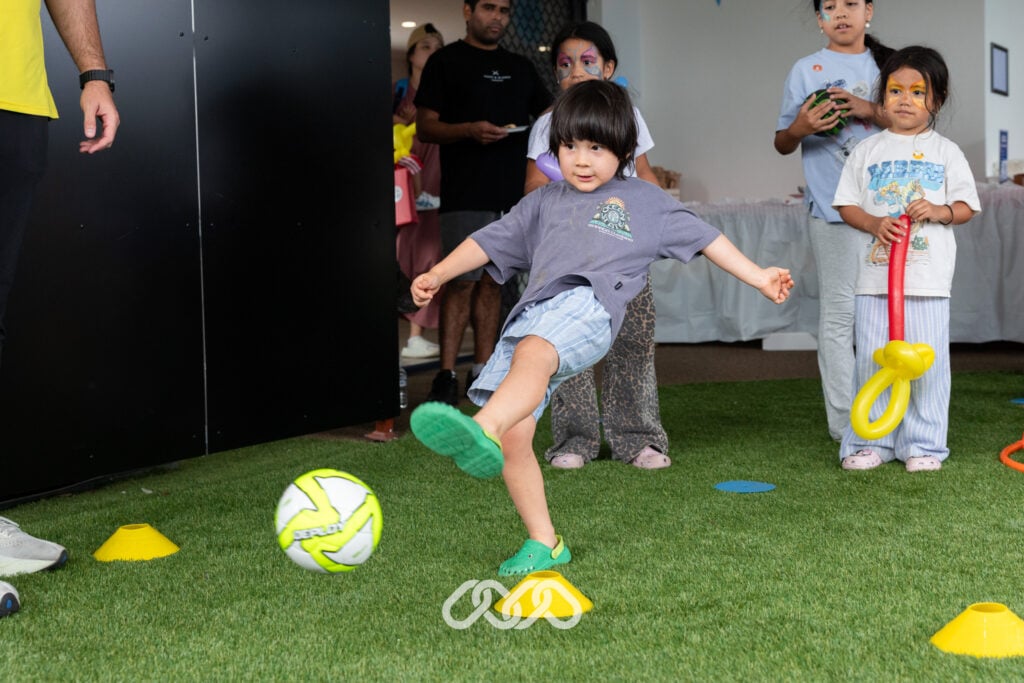 Child kicks small soccer ball in outdoor area at Riverwood Montessori Academy Grand Opening