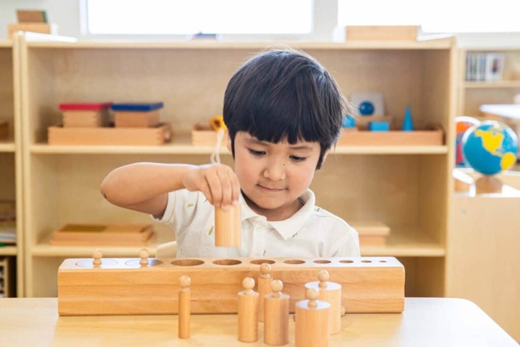 Montessori Toddler working with Cylinder Blocks in Toddler Classroom