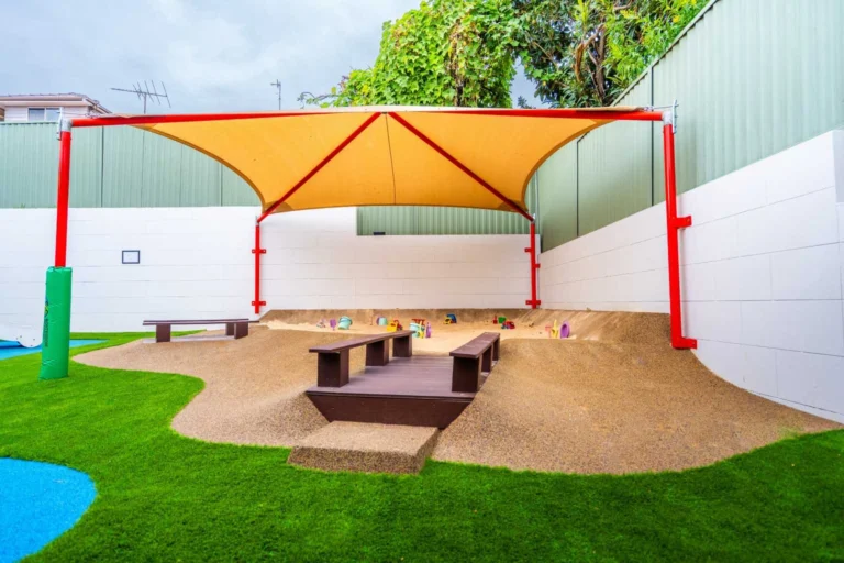 Large outdoor sandpit area covered by a shade sail.