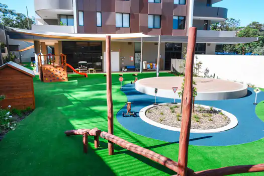 Outdoor playground at Lane Cove West Montessori Academy featuring natural timber balancing equipment, soft fall surfaces, and open play spaces designed for active learning and exploration.