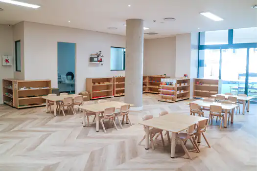 Bright preschool Montessori classroom at Lane Cove West Montessori Academy featuring natural timber tables, child-sized furniture, open learning spaces, and accessible Montessori materials.