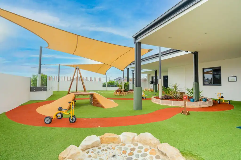 Shaded outdoor playground at Leppington childcare centre with tricycle path and nature play area