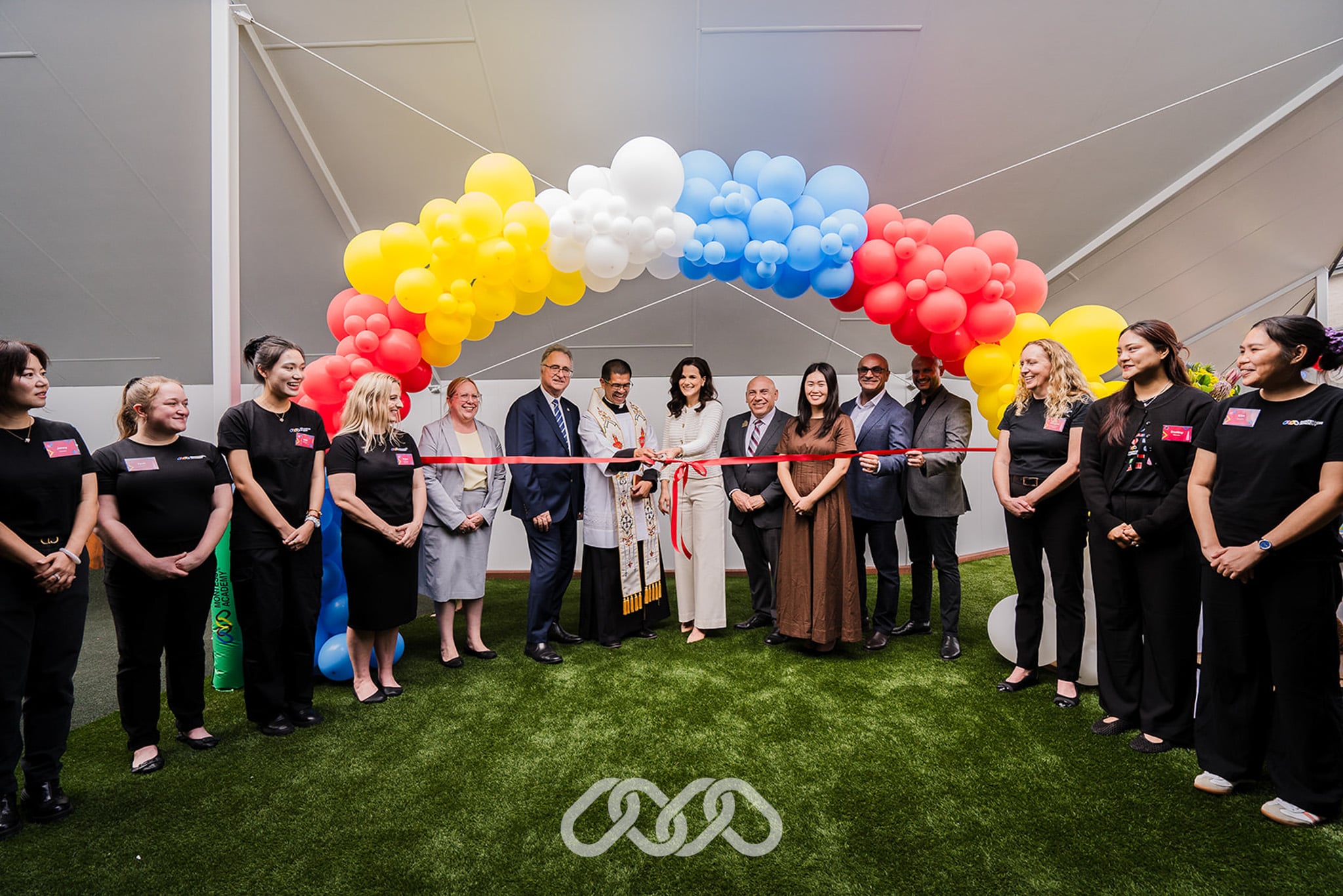 Montessori Academy leadership and community leaders gather under colourful balloon arch