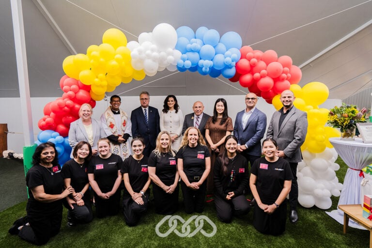 Leadership and centre team gather under colourful balloon arch outdoors at Crane Road Grand Opening