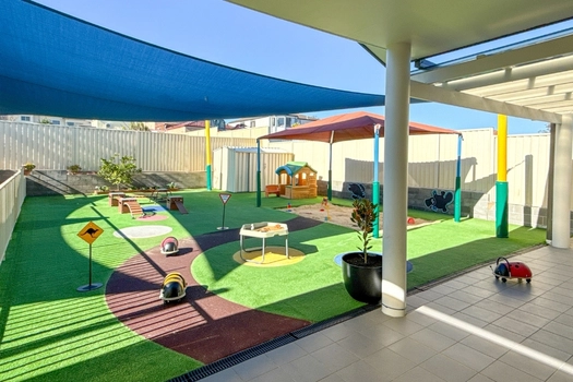 Shaded outdoor play area at Auburn Montessori Academy with tricycle path and garden play spaces