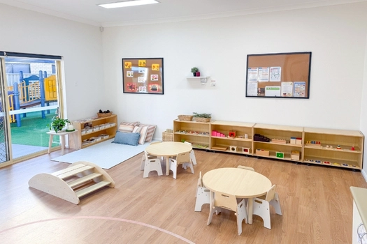 Bright Montessori learning room at Auburn Montessori Academy with round tables and open shelves