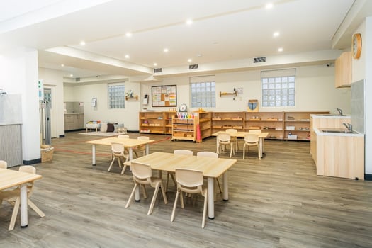 Montessori classroom with wooden shelves and child-sized tables at Balmain Road childcare centre
