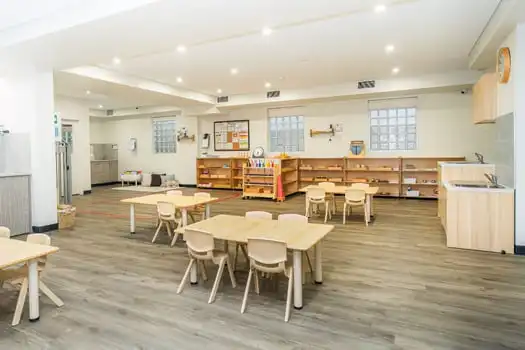 Montessori classroom with wooden shelves and child-sized tables at Balmain Road childcare centre