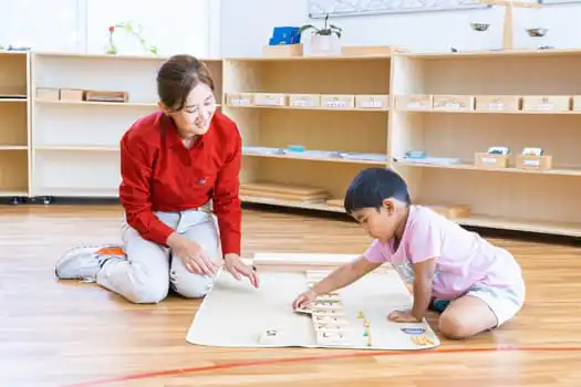 Educator presenting Montessori learning material to child at Chatswood childcare