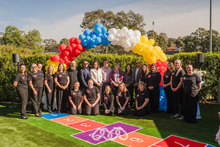 Educators, guests and community representatives at the Narellan Vale Montessori Academy Grand Opening beneath a colourful balloon arch.